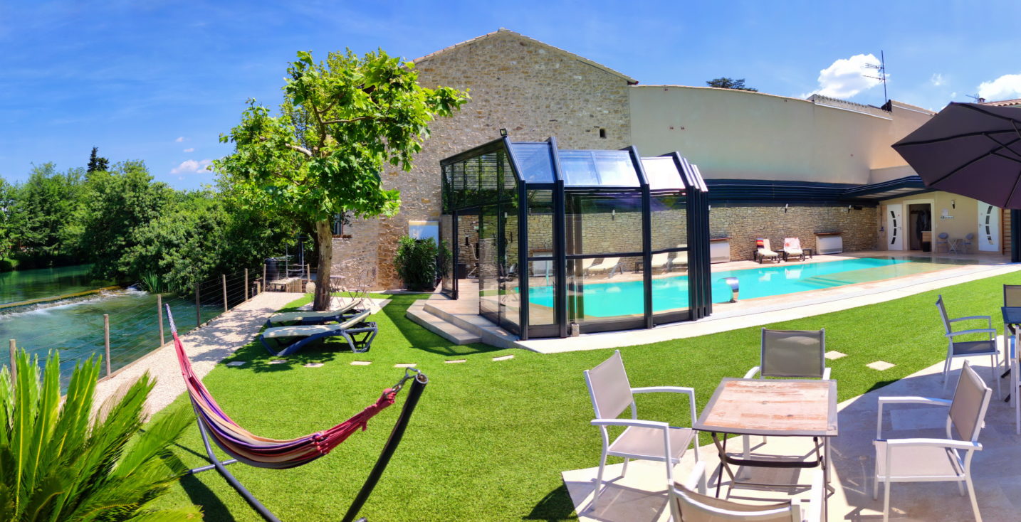 Piscine et terrasses en bord de Sorgue, avec salons de jardin, bains de soleil et hamacs, pour une invitation à la sieste ou à l'apéritif